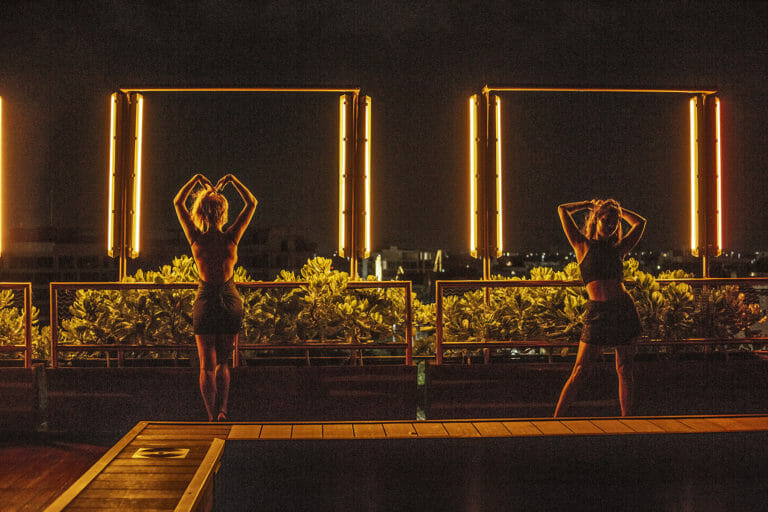 Nightview of therooftop of residencia condos with 2 woman posing towards the ocean